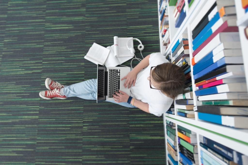 Student in a library using a laptop