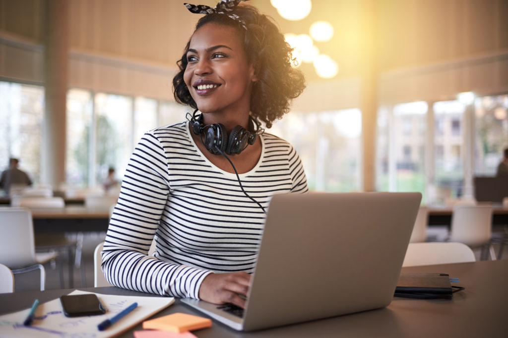 Student smiling while working at a laptop