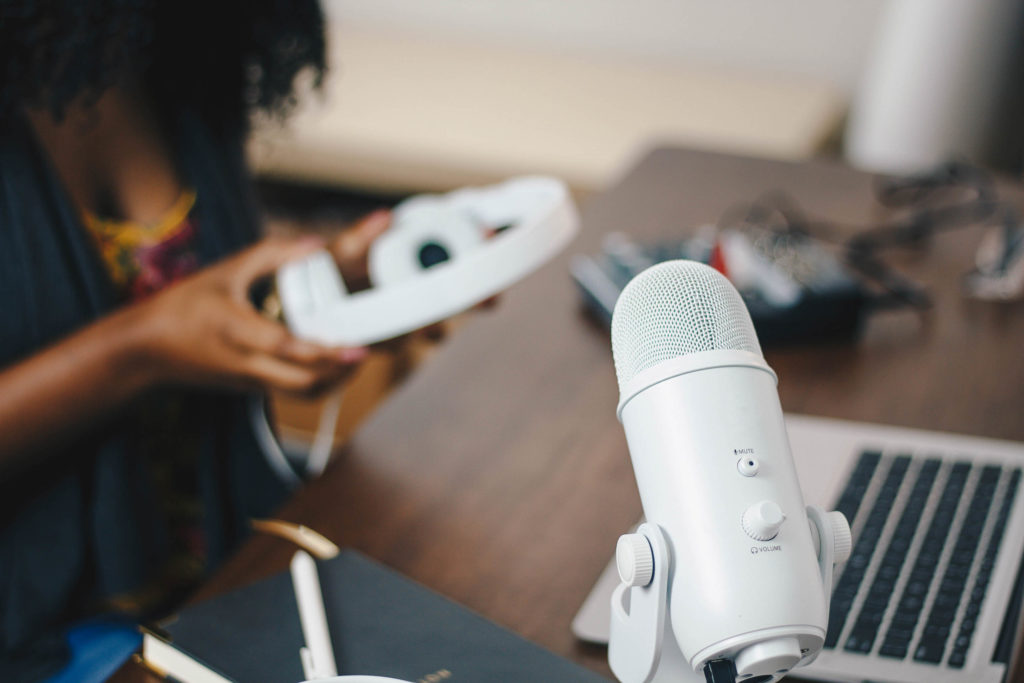 Woman holding headphones near a laptop and microphone